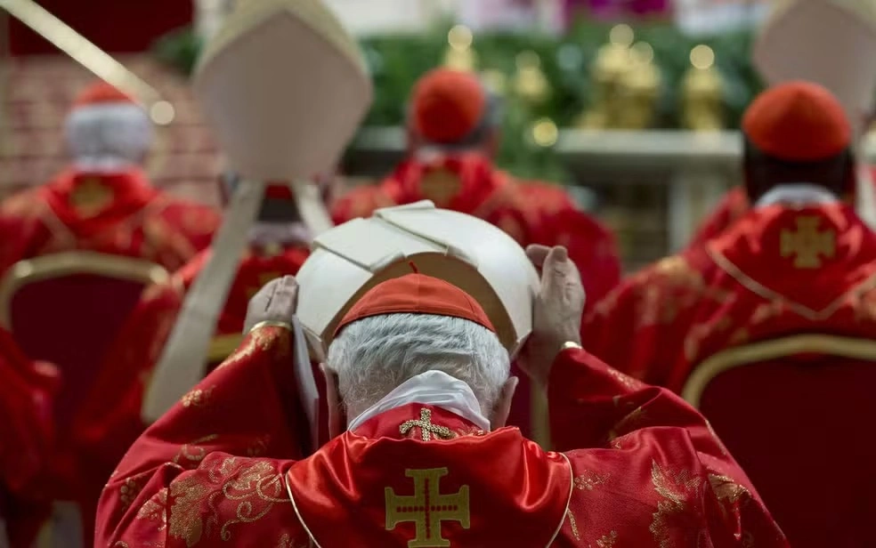 Cardeal coloca sua mitra durante a missa do início do conclave